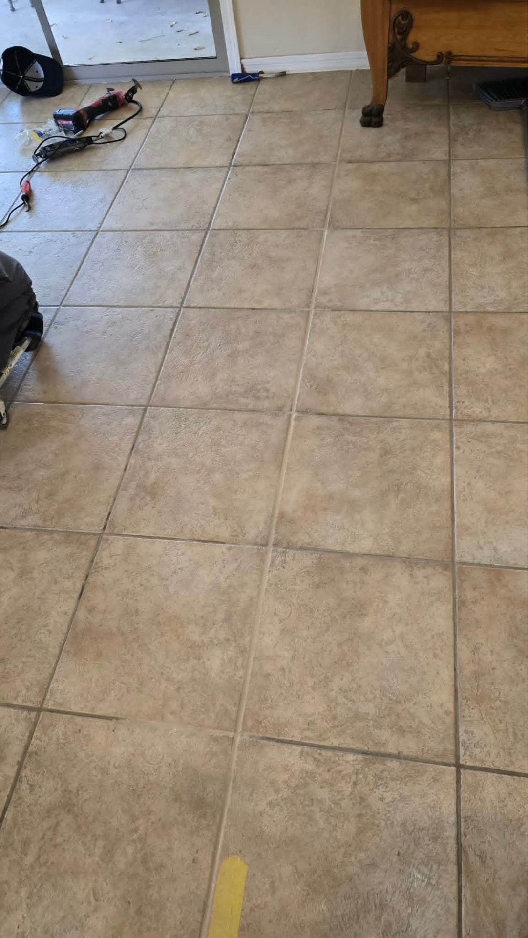 Oscillating tool and grout removal blades on a beige ceramic tile floor in Gilbert AZ during a hollow tile and cracked grout repair before color sealing