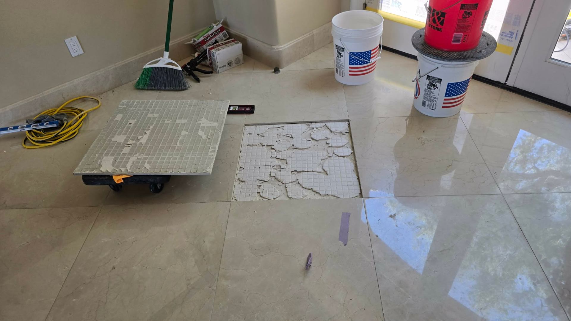 Underside of a removed marble tile from a Paradise Valley home showing patchy spot bonded mortar coverage with bare backer visible across most of the tile back